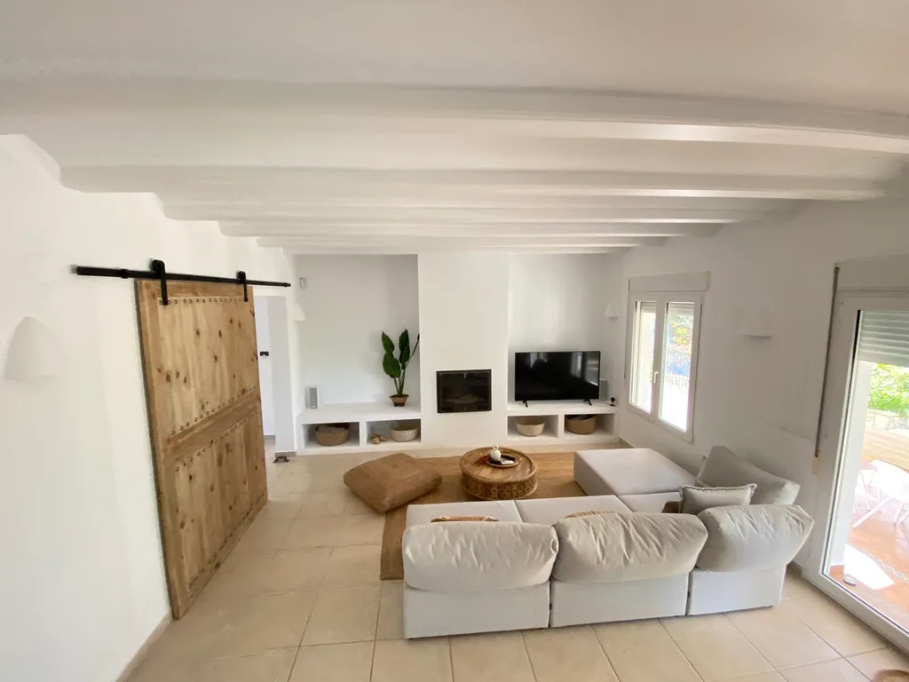 Salón reformado en villa de Jávea con vigas y puerta corredera