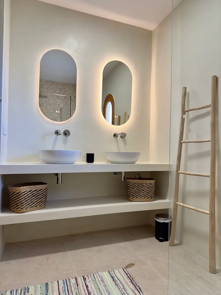 Baño en microcemento con doble lavabo y espejos retroiluminados