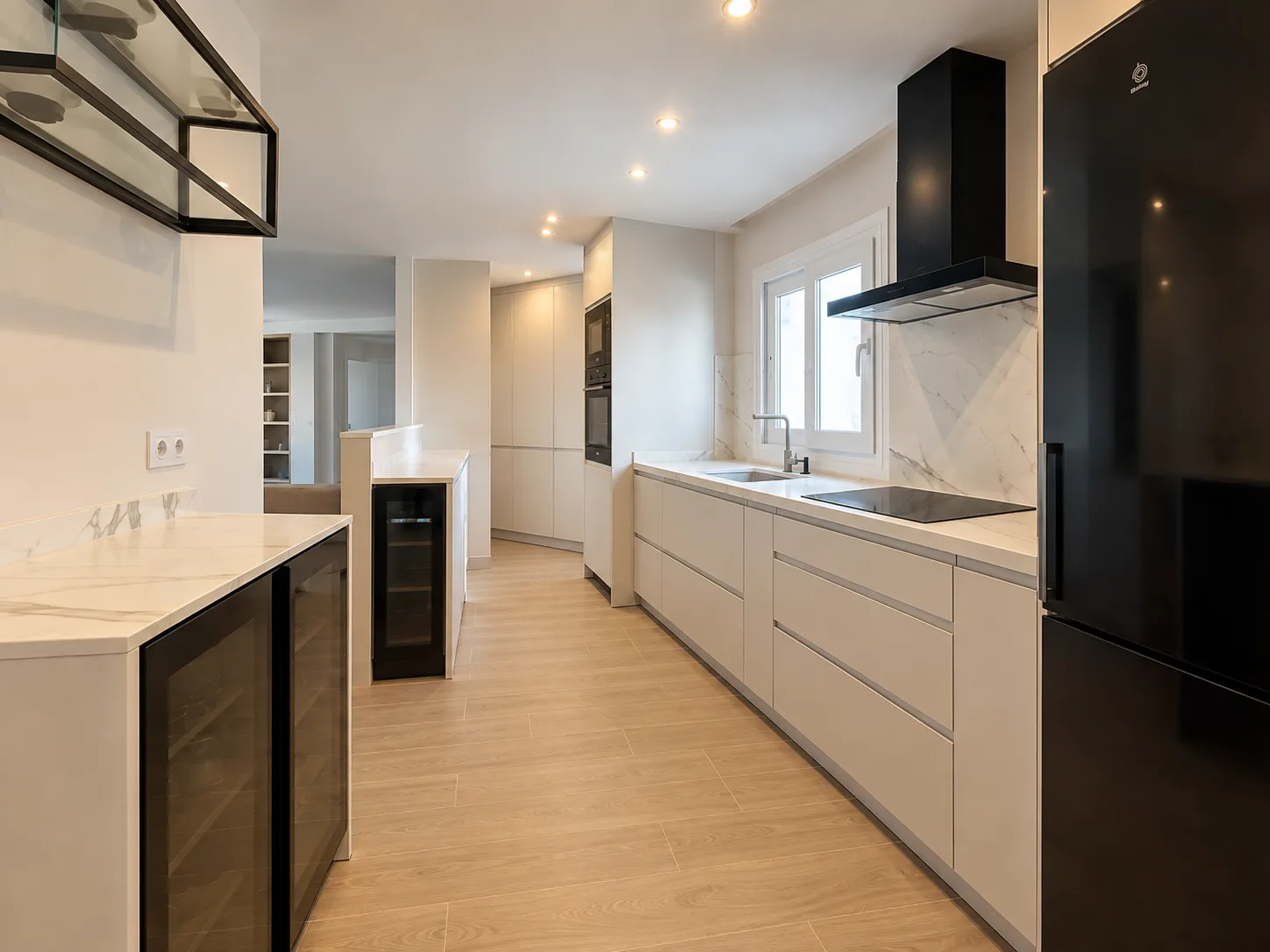 Cocina en paralelo en Málaga con muebles blancos mate, encimera efecto mármol y vinotecas integradas